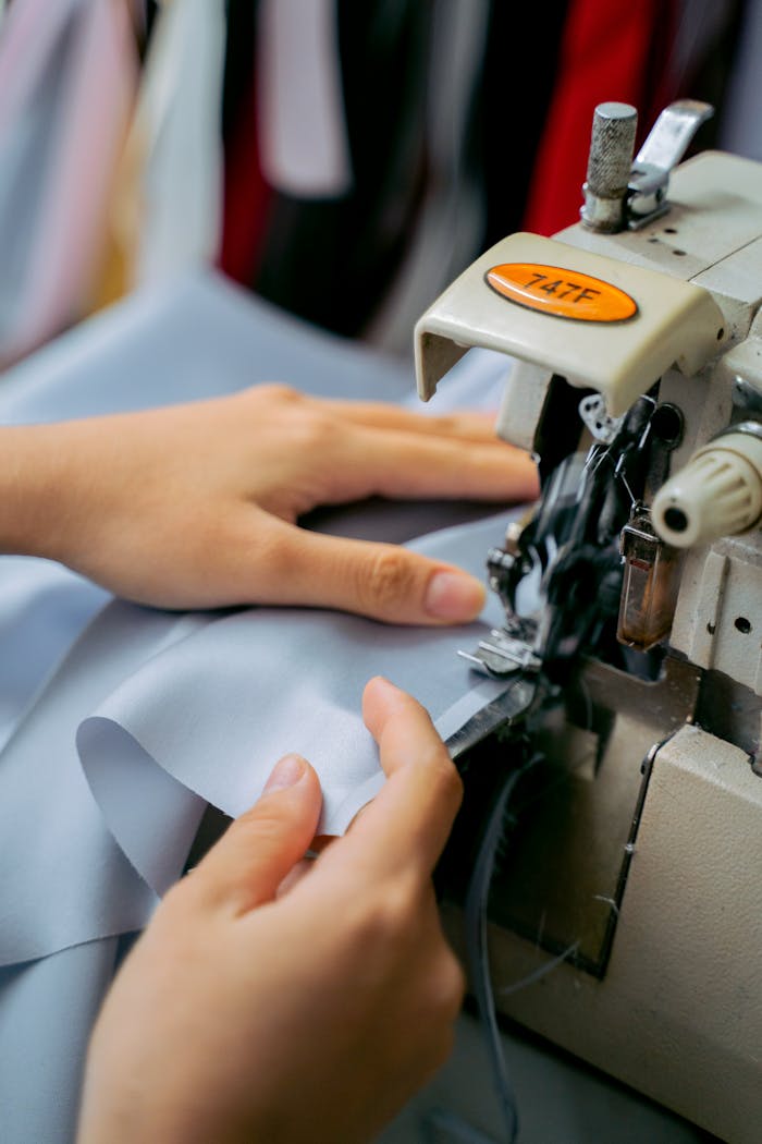 our-services-3 Close-up of hands sewing fabric with a sewing machine, showcasing handmade craftsmanship.